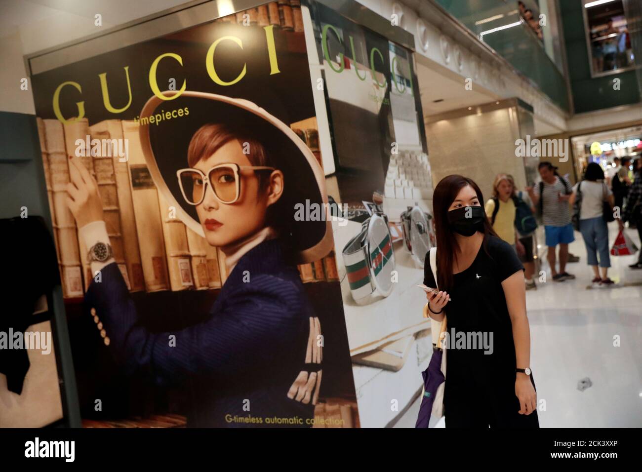 A woman walks past a Gucci advertising poster as shoppers and  anti-government protesters gather at New Town Plaza in Sha Tin, Hong Kong,  China November 3, 2019. REUTERS/Shannon Stapleton Stock Photo -