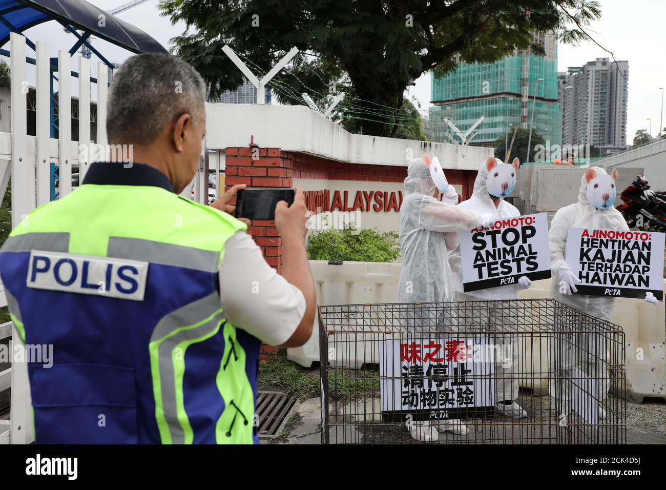 A police officer takes a picture of activists from PETA (People for the Ethical Treatment of Animals), dressed as rats, protesting against what they say is Ajinomoto's use of animal testing outside the company's headquarters in Kuala Lumpur, Malaysia, November 28, 2019. REUTERS/Lim Huey Teng Stock Photo