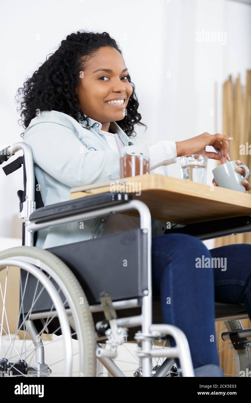 happy woman on a wheelchair eating dinner at home Stock Photo - Alamy