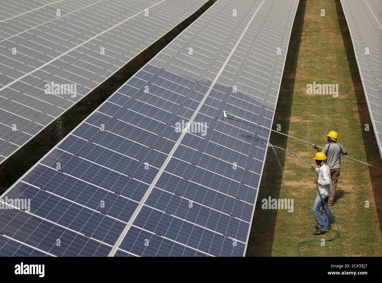 Workers clean photovoltaic panels inside a solar power plant in Gujarat, India, in this July 2, 2015 file photo. The likely collapse of SunEdison Inc's solar project in India, the first of 32 planned "ultra mega" complexes, could delay Prime Minister Narendra Modi's goal to increase renewable energy fivefold by several years and probably cost consumers more. REUTERS/Amit Dave/Files Stock Photo