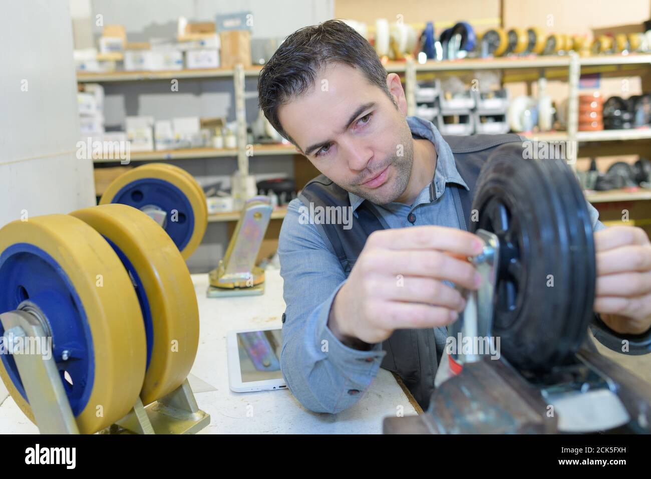 man fitting trolley wheel and tightening bolts Stock Photo Alamy
