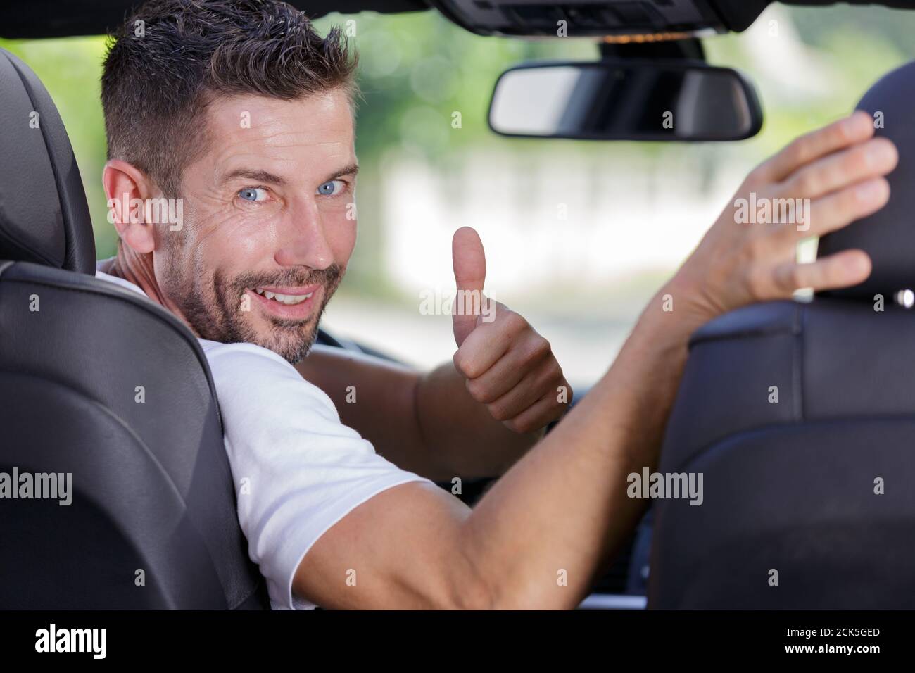 man behind wheel showing thumbs up sign Stock Photo - Alamy
