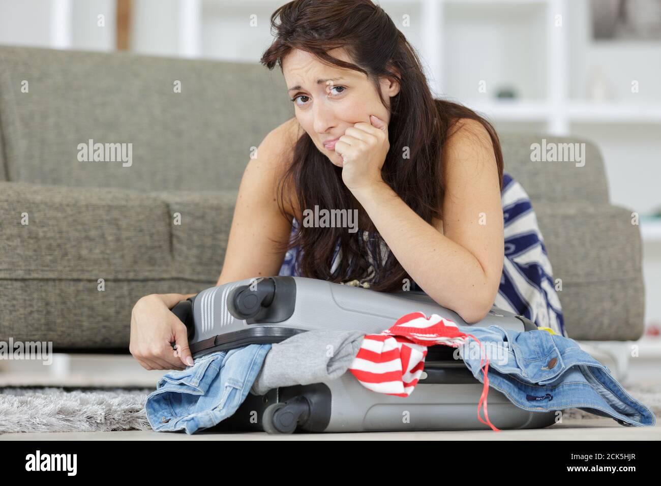 exhausted young woman packing luggage Stock Photo - Alamy