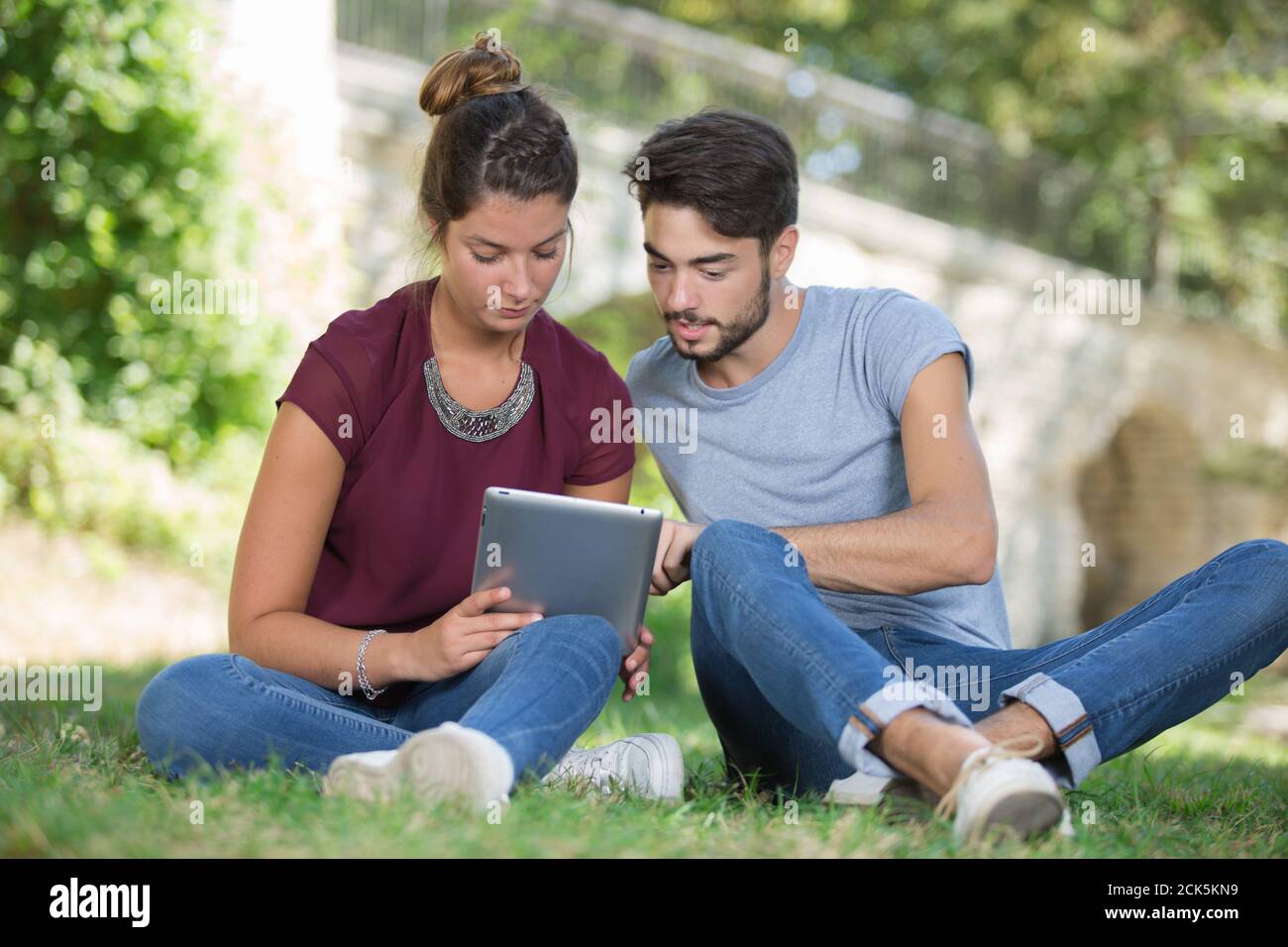 smiling young couple talking and using tablet outdoors Stock Photo