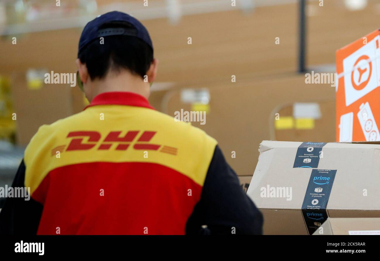 An employee of German postal and logistics group Deutsche Post DHL is  pictured beside an Amazon