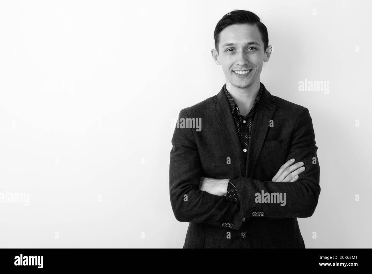 Studio shot of young happy businessman smiling with arms crossed ...