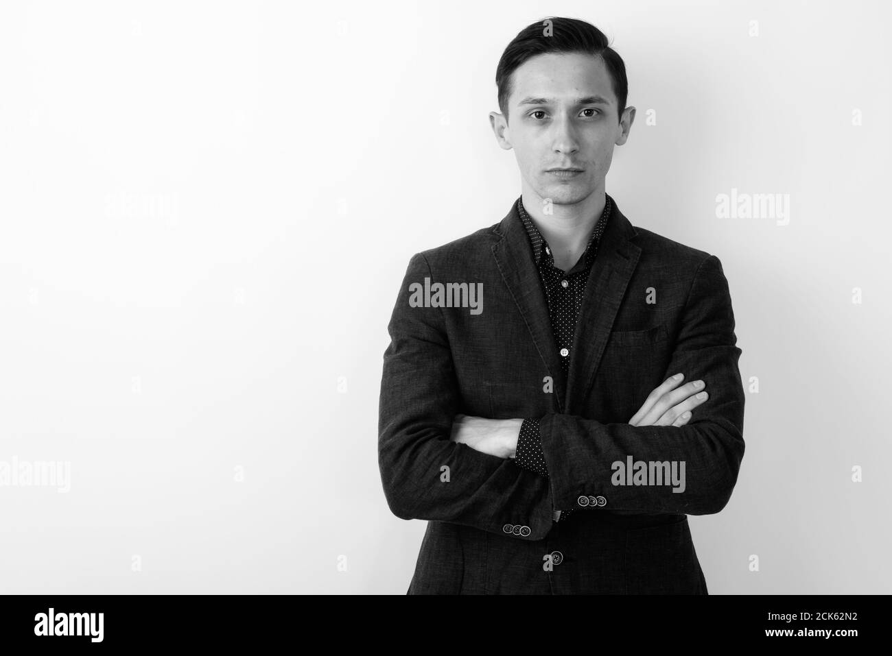 Studio shot of young handsome businessman with arms crossed against ...