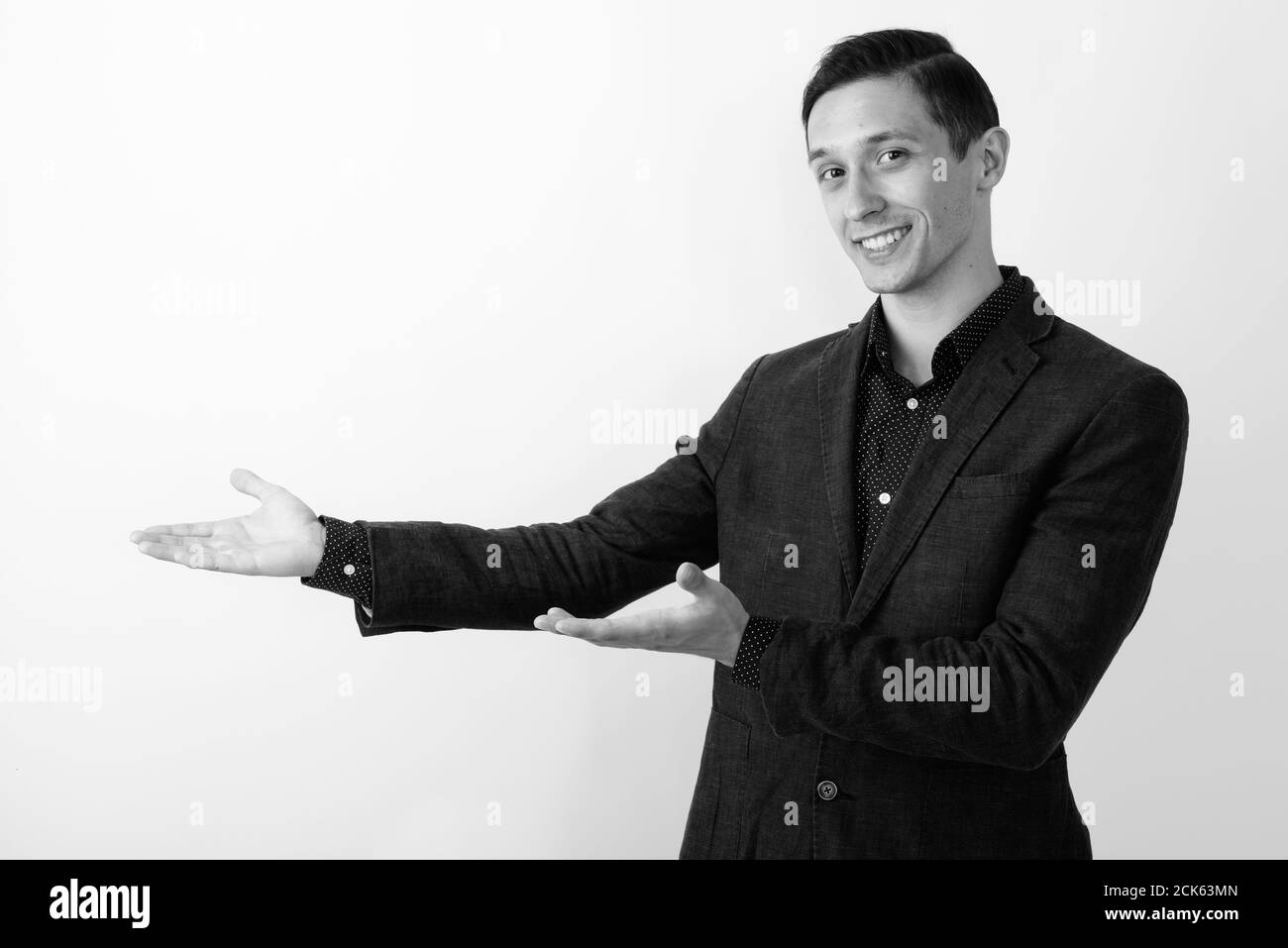 Studio shot of young happy businessman smiling while showing something ...