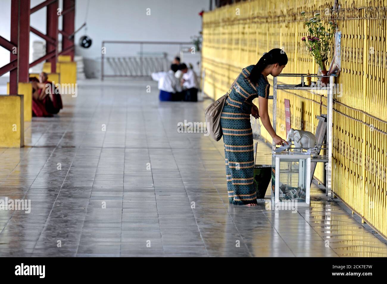 A woman at the Chauk Htat Gyi Pagoda in Yangon making a money offering to a Buddhist deity. Myanmar (Burma) Stock Photo
