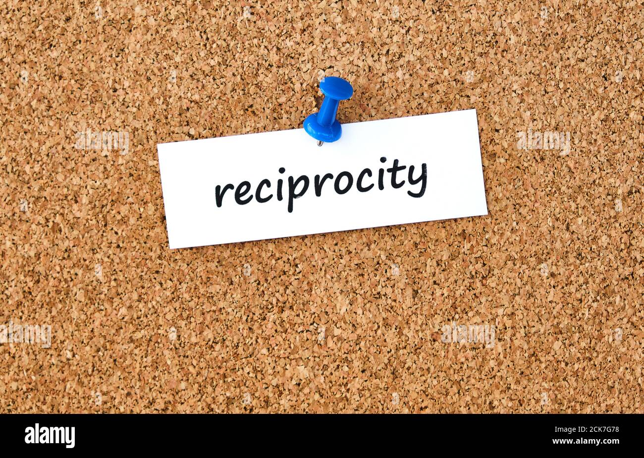 Reciprocity. Word written on a piece of paper or note, cork board background. Stock Photo