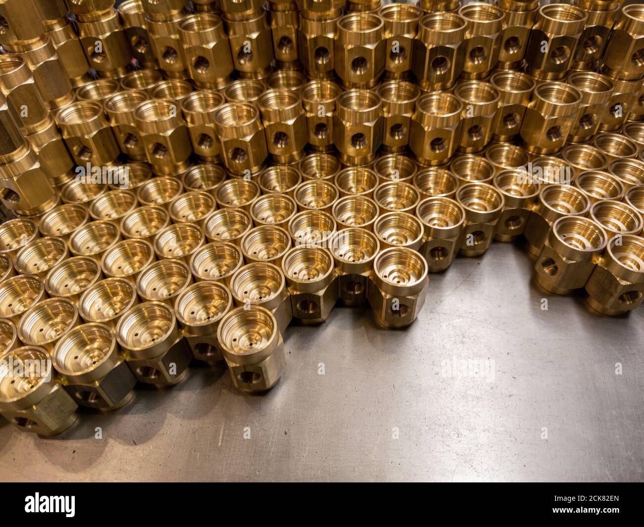 Shiny yellow metal parts background. Shiny brass metal threaded hexagonal parts after turning and machining. Stock Photo
