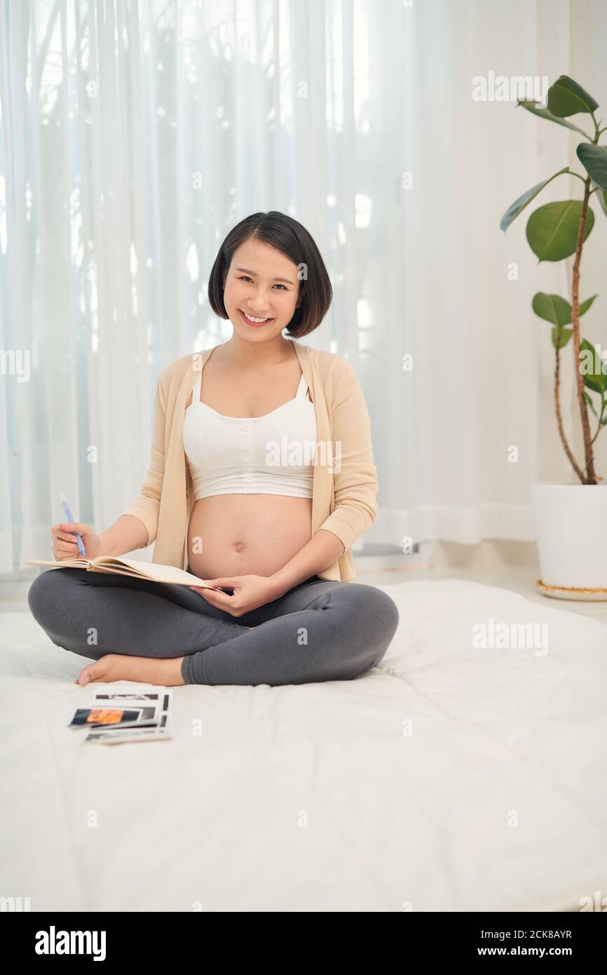 regnant woman lie down looking at a sonogram ultrasonography picture of her unborn baby Stock Photo