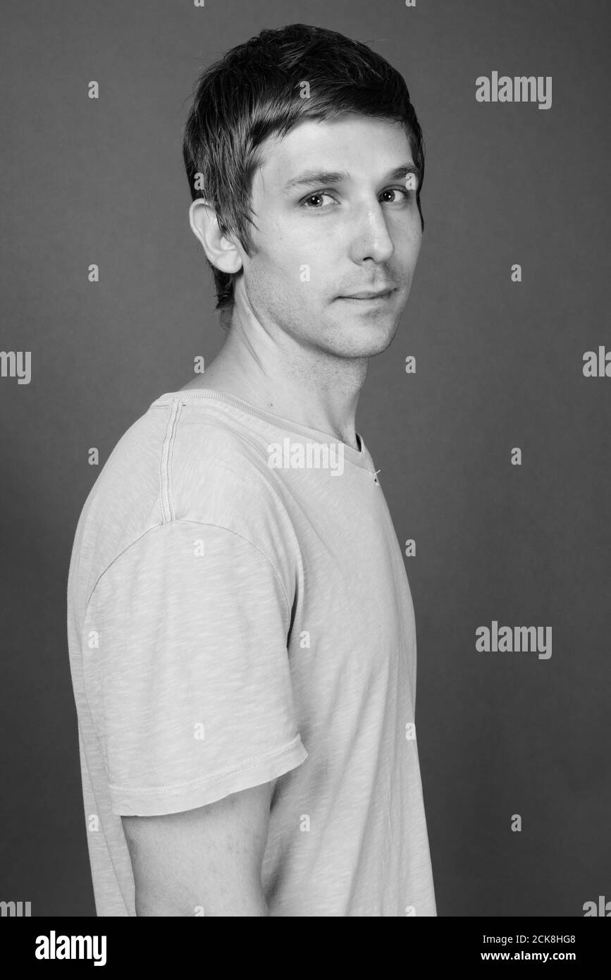 Portrait of young handsome man against gray background Stock Photo - Alamy