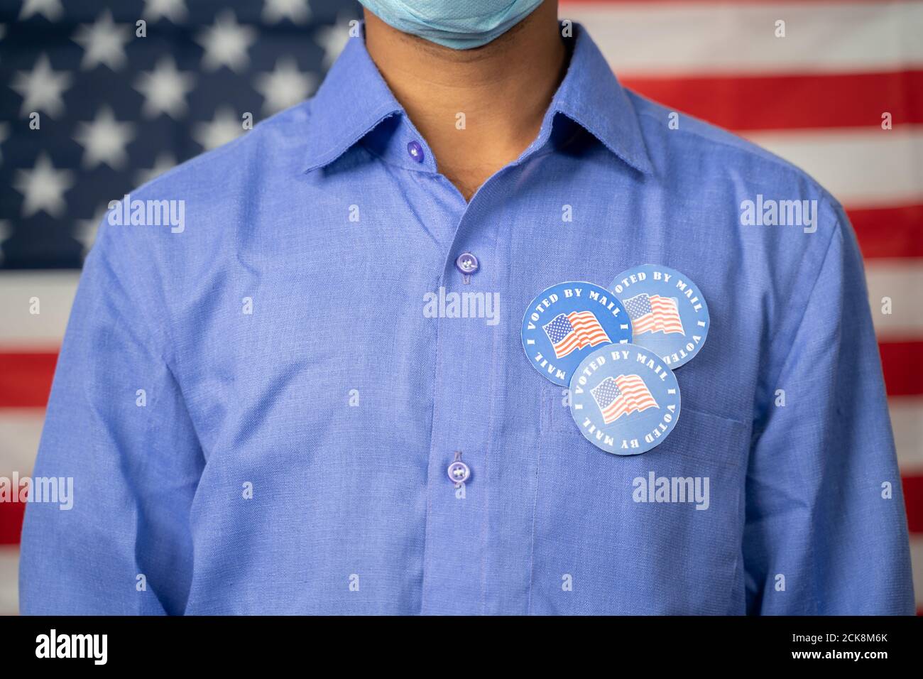Unrecognizable Man with multiple I voted by mail sticker on shirt with US flag as background - Concept of fraud in US election mail-in voting or vote Stock Photo