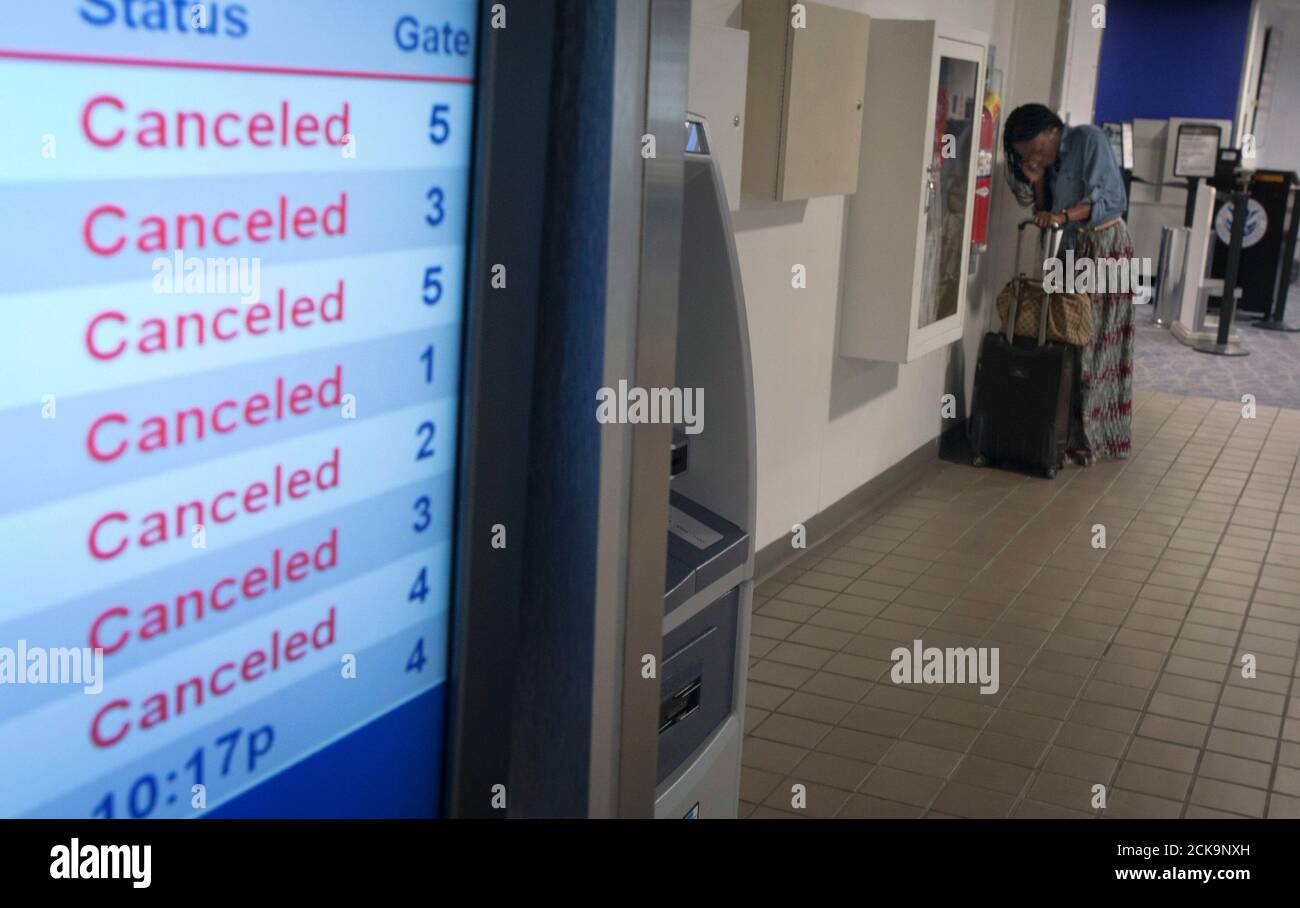 A woman speaks on her phone near a screen that displays information on cancelled flights, after a Southwest Airlines Boeing 737 made an emergency landing at LaGuardia airport in New York July 22, 2013. Several people were injured when the Southwest Airlines Flight 345 with 150 people on board landed at New York City's LaGuardia Airport without its nose gear, officials said.    REUTERS/Carlo Allegri  (UNITED STATES - Tags: BUSINESS TRANSPORT DISASTER) Stock Photo