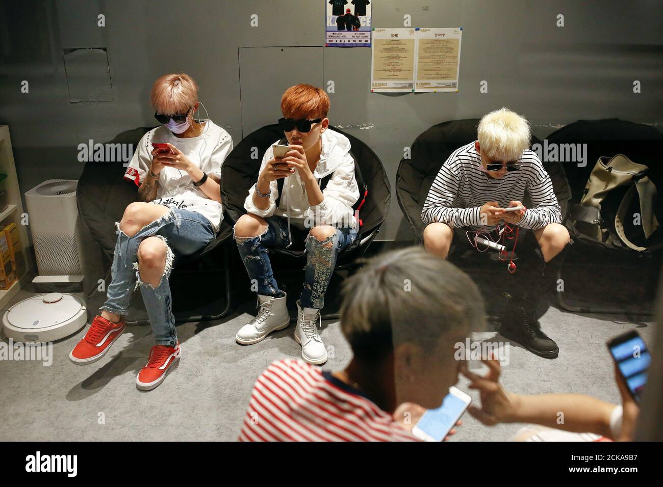 Members of China's all-girl 'boyband' FFC-Acrush use their phones before a rehearsal at a dance studio in Beijing April 27, 2017. Picture taken April 27, 2017. REUTERS/Thomas Peter Stock Photo
