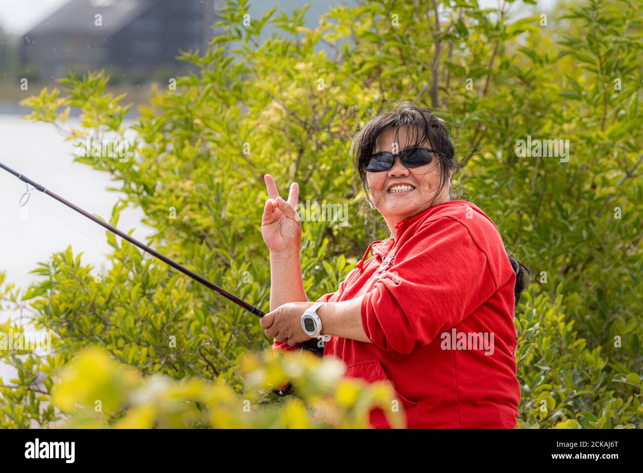 Woman holding fishing rod looking at camera hi-res stock