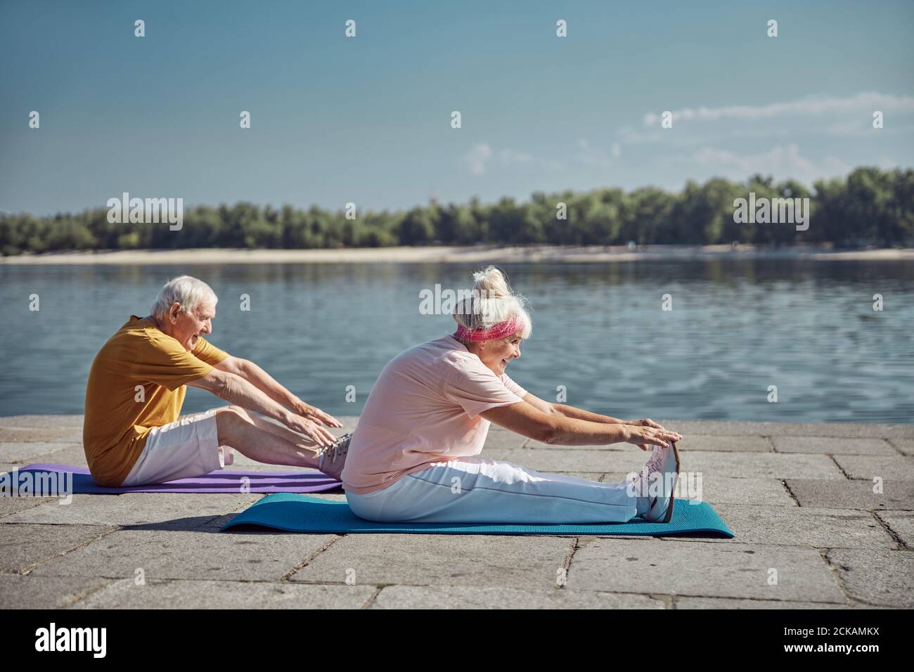 Two senior beginner yogis performing a stretching exercise Stock Photo