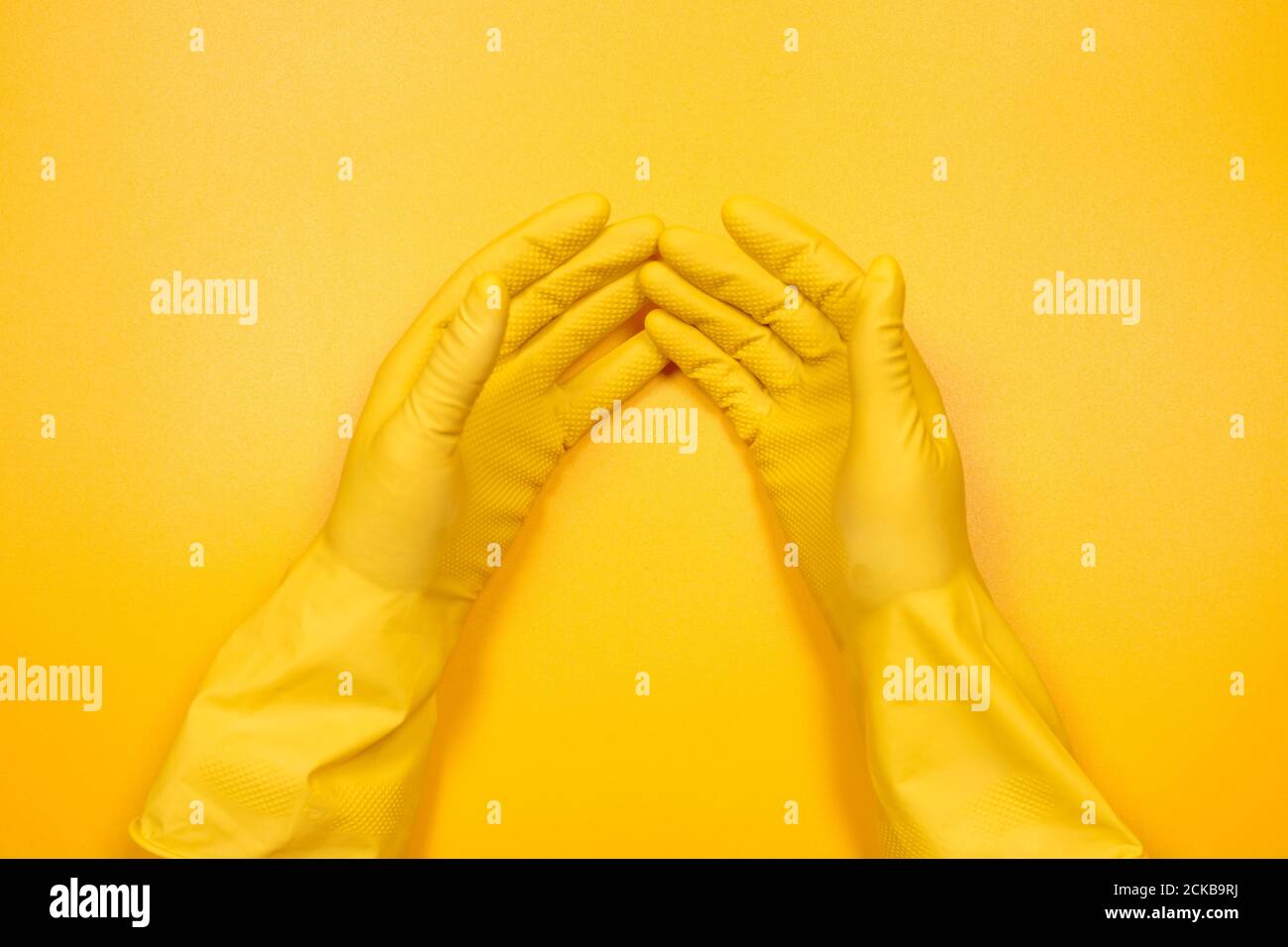 hands in yellow gloves on a yellow background. Stock Photo
