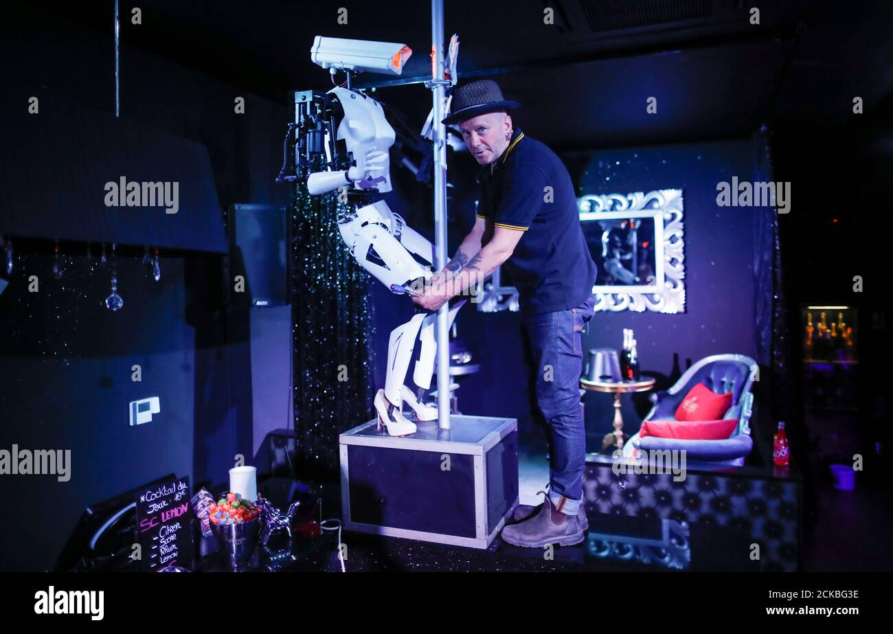 British artist Giles Walker looks on as he adjusts a pole-dancing robot  during its installation