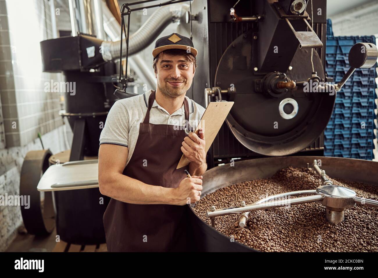 Handsome young man standing by coffee roasting machine Stock Photo