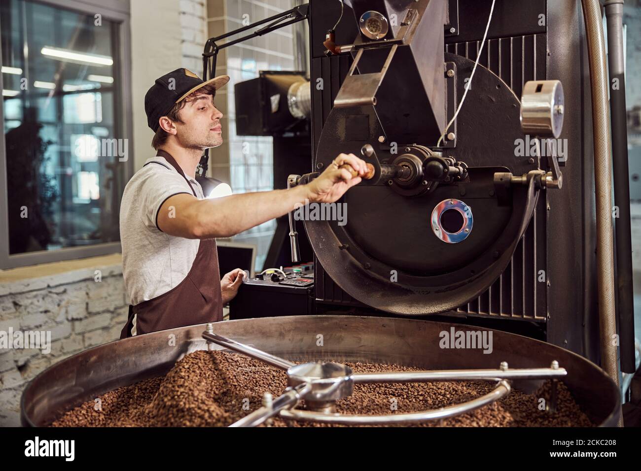 Handsome young man using industrial coffee roasting machine Stock Photo