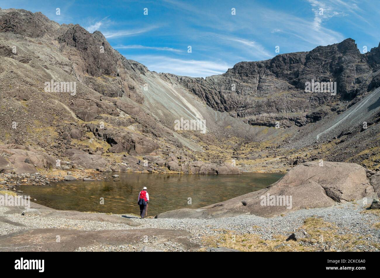Lone female walker by waters of Coire Lagan with Cuillin Ridge above in the Black Cuillin Mountains, Isle of Skye, Scotland, UK Stock Photo