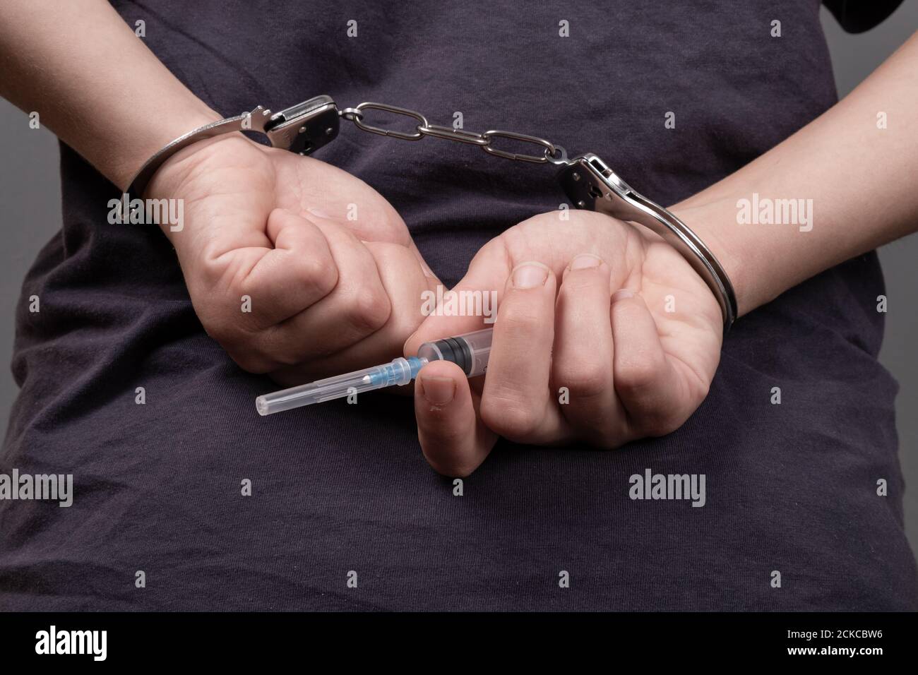 drug trafficking, a man in handcuffs with a syringe. Stock Photo