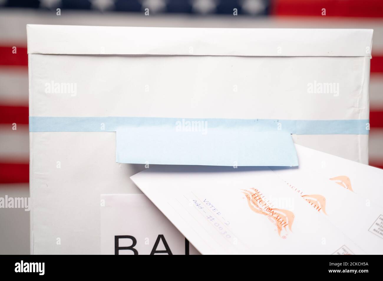 Maski, India 14 September, 2020 : Concept of Mail in vote at US election - Closeup of hands putting Multiple mails inside the ballot box with us flag Stock Photo