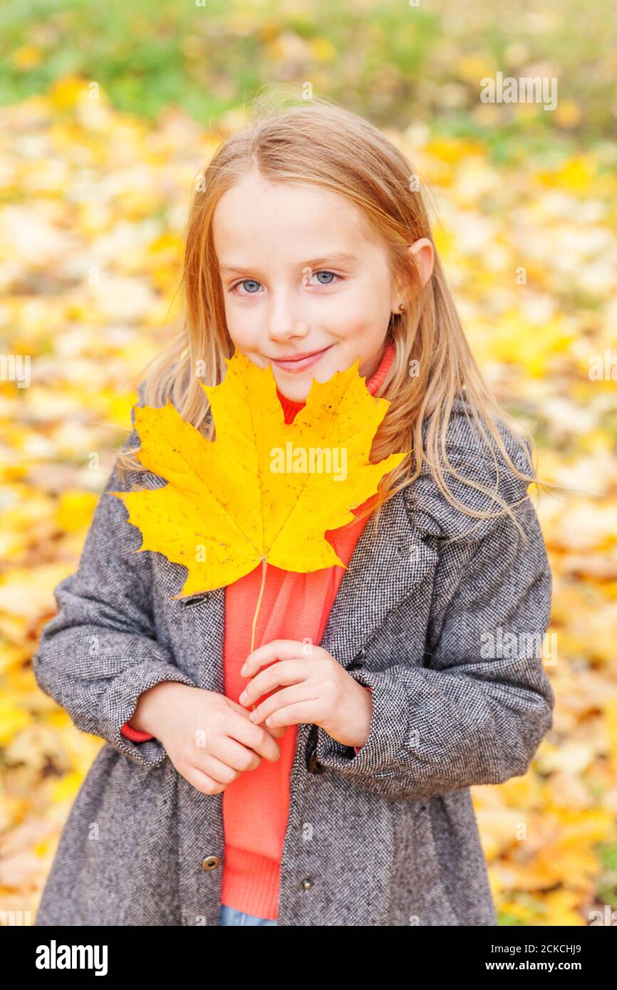 Happy young girl playing with falling yellow leaves in beautiful autumn ...