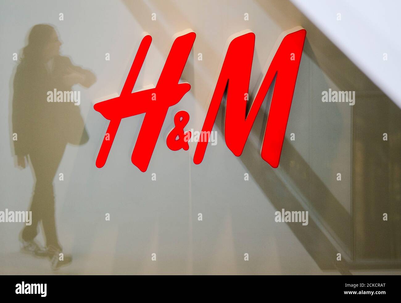 A woman is reflected next to the logo of the H&M fashion retailer in the  newly opened Mall of Berlin shopping centre in Berlin, September 25, 2014.  A gigantic German department store