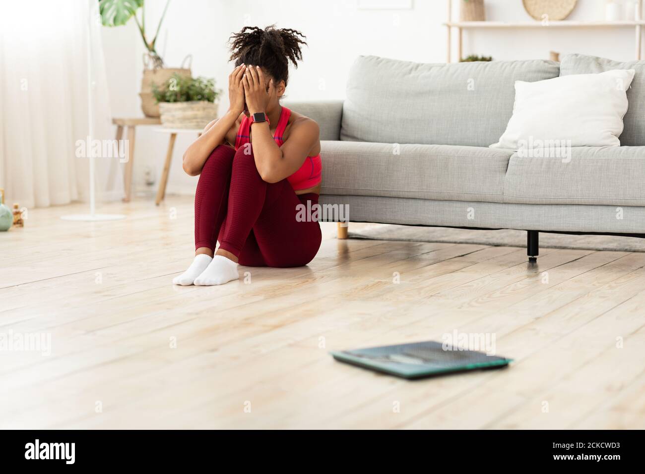 Desperate African Girl Sitting Near Scales Crying After Weighing Indoor Stock Photo