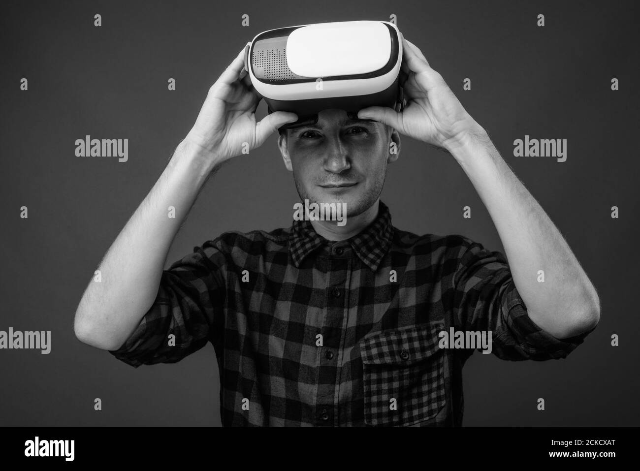 Portrait of hipster man with VR glasses against gray background Stock Photo