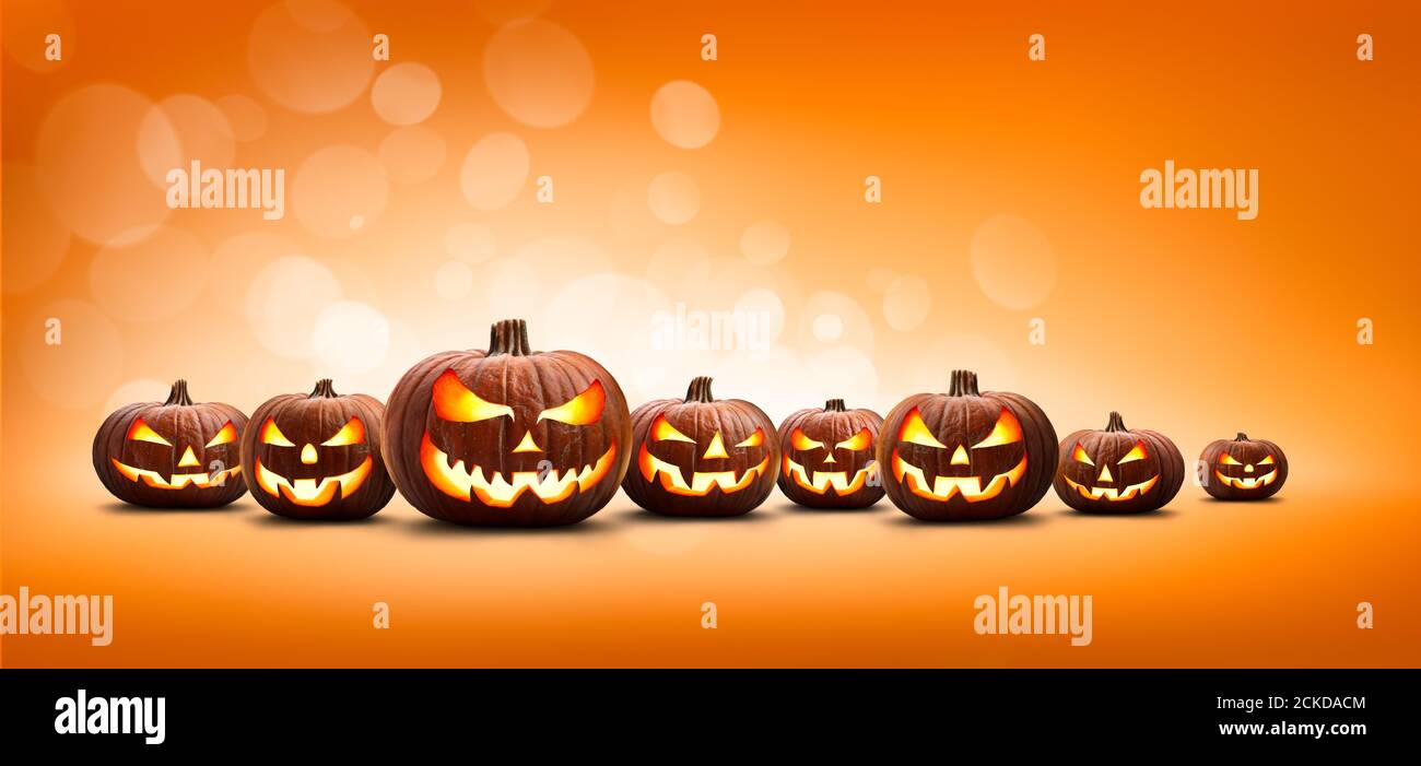 Nine halloween, Jack O Lanterns, with evil spooky eyes and faces isolated against a orange and yellow bokeh lit background. Stock Photo