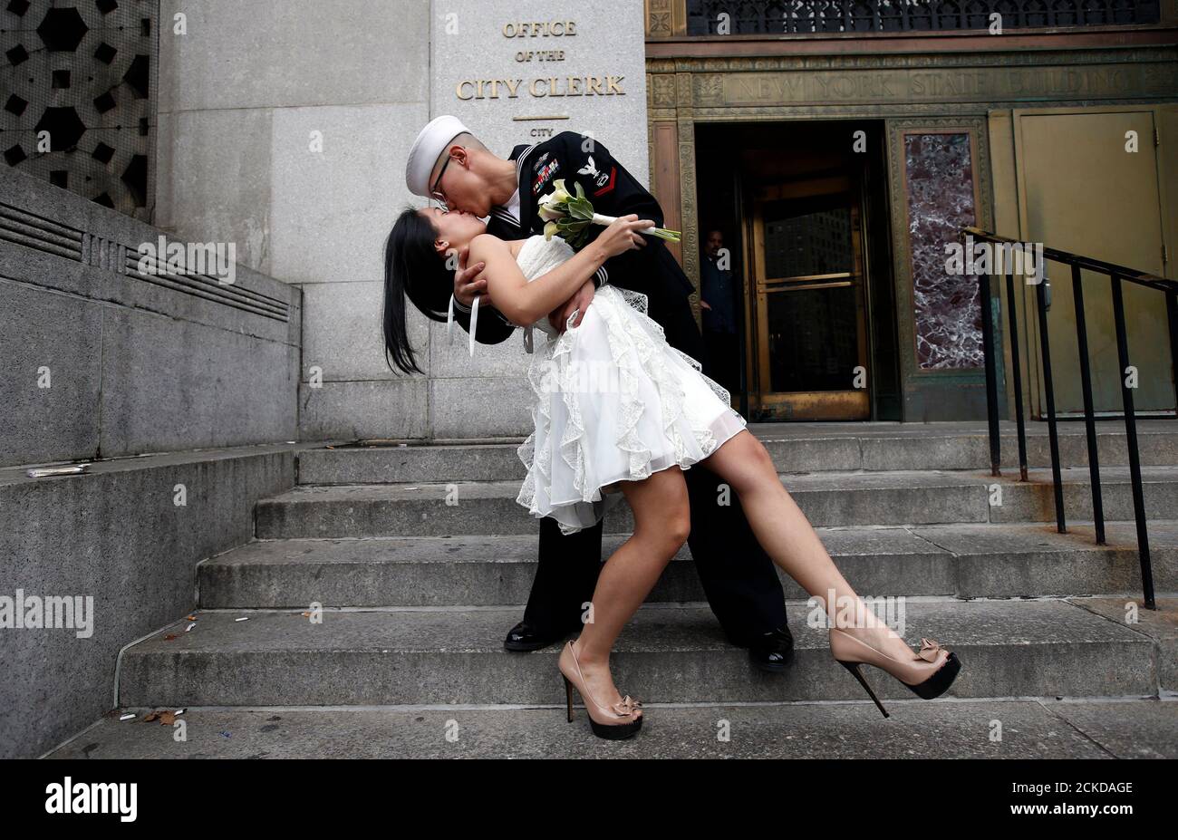 U.S. Navy Petty Officer 3rd Class EO3 John Chen, 23, from Lakehurst, New Jersey, kisses his new bride Victoria Chan, 25, from Manhattan, as they pose for photographers after they were married in a civil ceremony at New York City's Office of the City Clerk December 12, 2012. Hundreds of couples packed the office in lower Manhattan to be married on the date 12/12/12 as this will be the last such triple date for almost a century until January 1, 2101.  REUTERS/Mike Segar    (UNITED STATES - Tags: SOCIETY PORTRAIT) Stock Photo