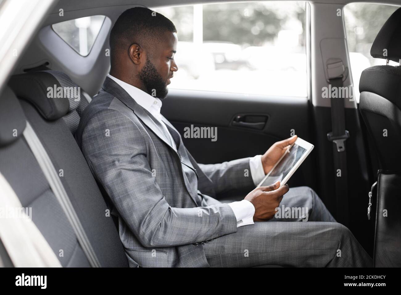 Concentrated black guy manager using digital tablet in car Stock Photo