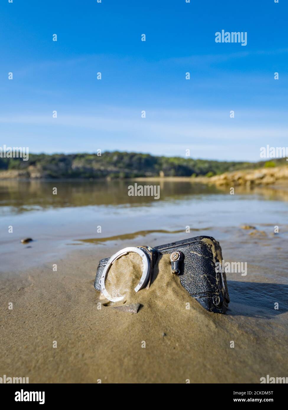 Nikon retro classic SLR film camera body on beach inverted upside down upsidedown calm calmness smooth serenity serene water surface Stock Photo