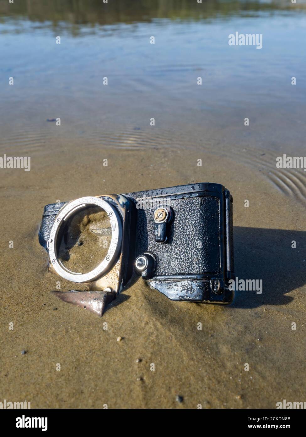 Nikon retro classic SLR film camera body on beach inverted upside down upsidedown Stock Photo