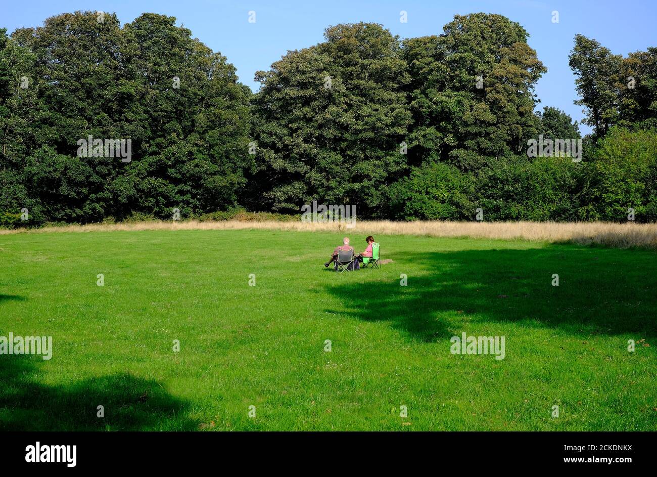 two senior people sitting on seats in field, self isolation during lockdown, norfolk, england Stock Photo