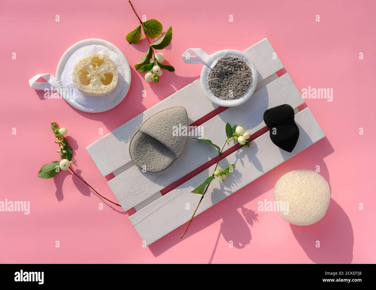 various types of face sponges for make up removing and cleaning face. konjak and loofah or luffa sponge, reusable cleaning pads and flowers on trendy pink background.face cleaning concept. Stock Photo