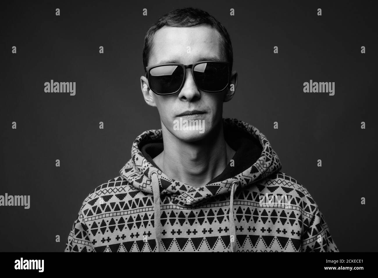 Portrait of young man wearing hoodie against gray background Stock Photo