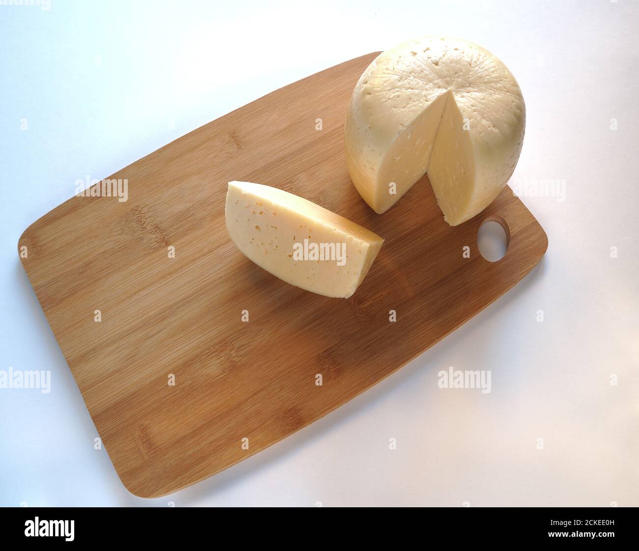 Cheese. Round cheese head on a wooden Board. Piece of cheese. Stock Photo