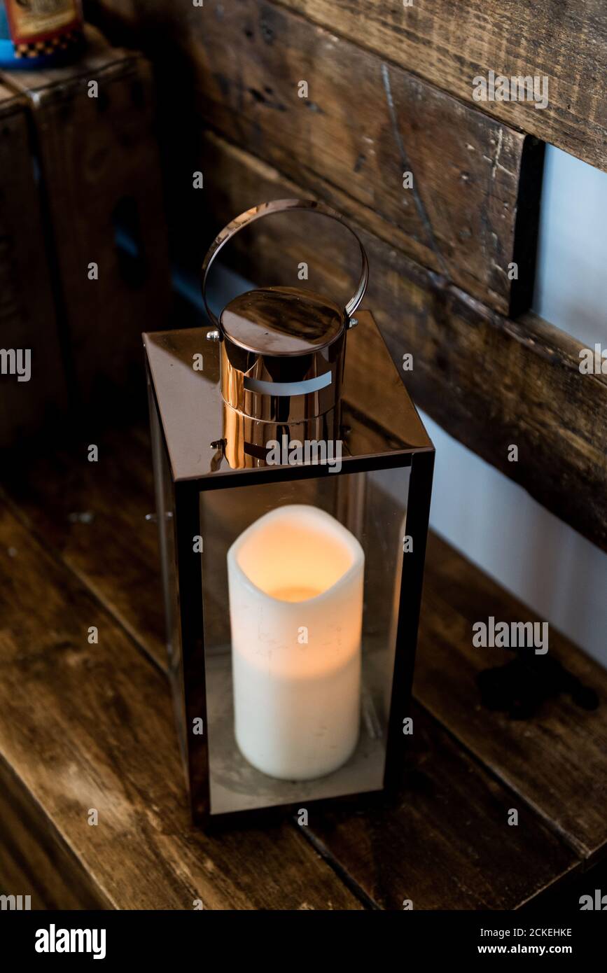 White Pillar Candle in metal Lantern from above with wooden background