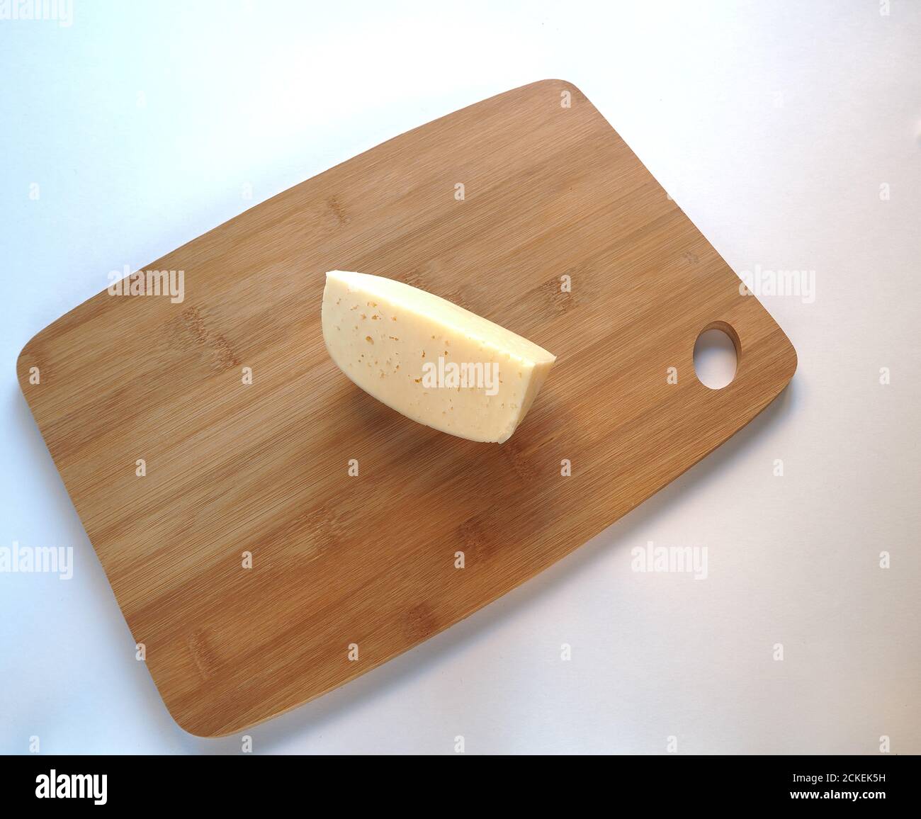 Cheese. Round cheese head on a wooden Board. Piece of cheese. Stock Photo