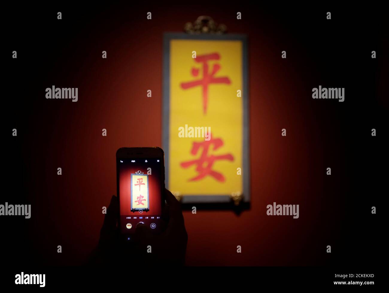 A visitor takes a picture of Chinese characters 'Ping an', which mean 'Safe and sound', during a museum exhibition to mark the upcoming Chinese Lunar New Year in the Forbidden City in Beijing, China January 30, 2019. REUTERS/Jason Lee Stock Photo