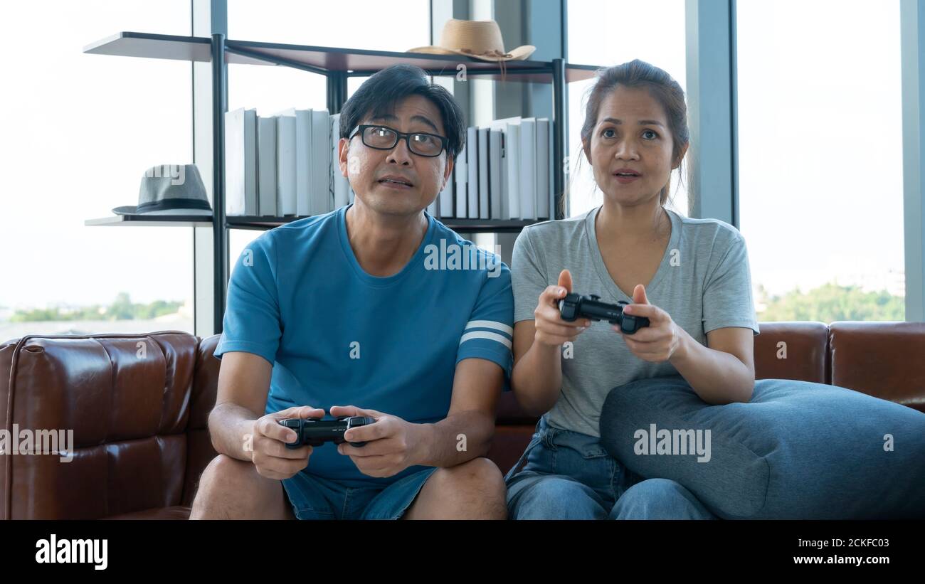 Old man and woman playing videogame at home Stock Photo