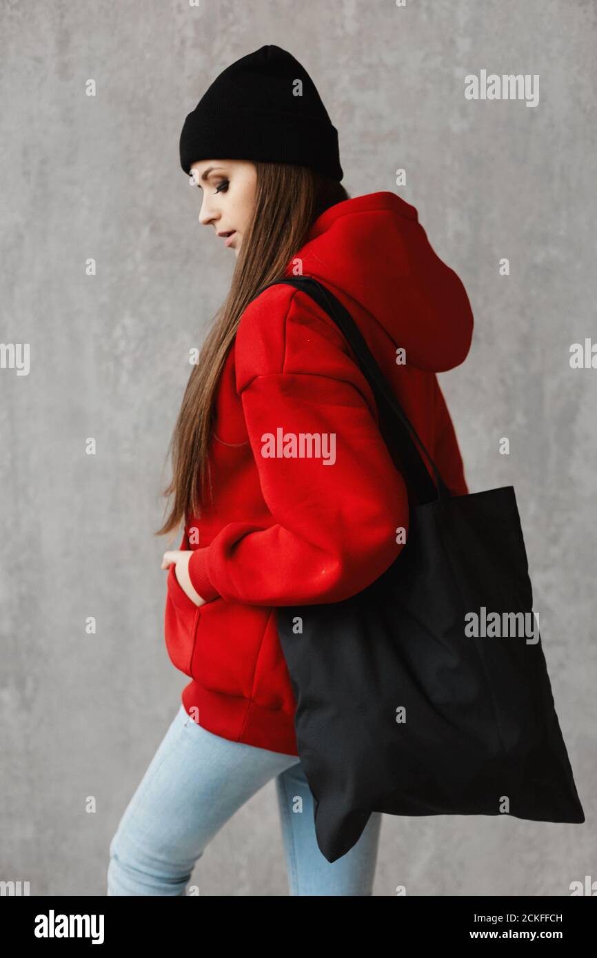 Download A Side View Of A Young Girl In A Red Hoodie And Black Hat With A Big Bag On Her Shoulder Stock Photo Alamy