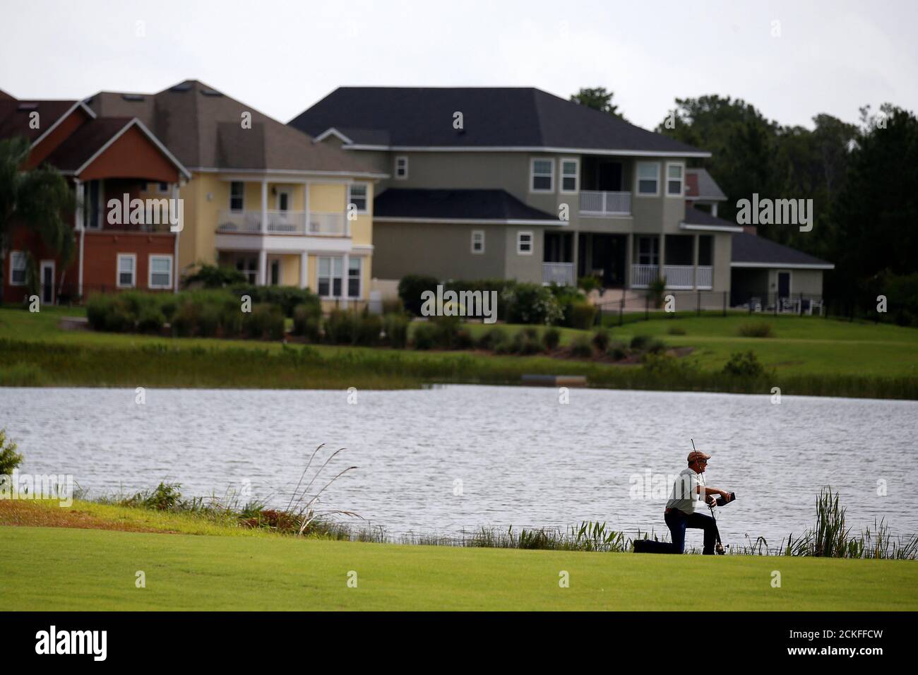 Alligator trapper Mark Whitmire kneels by a lagoon on a golf course to