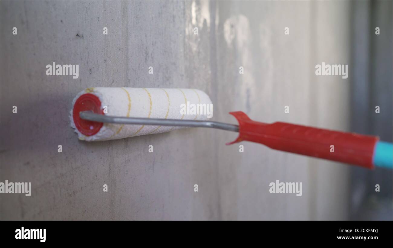 A worker primers the walls with a brush. Wall painting with primer