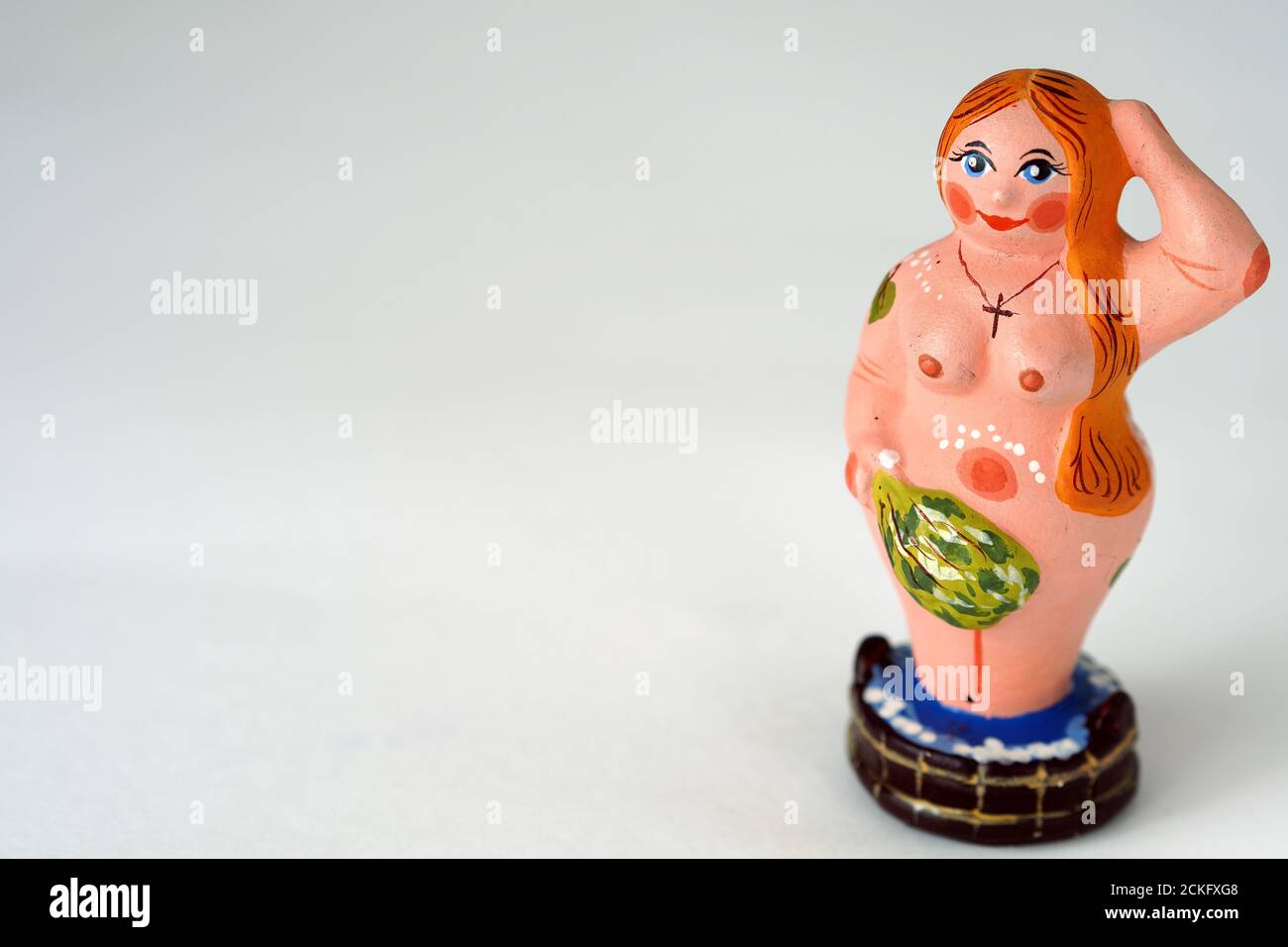 Funny figurine of ceramics, plaster and clay. A woman in a bath with a broom. Stock Photo